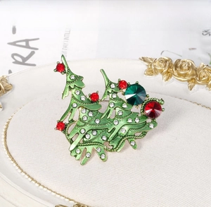 Detail of Christmas tree brooch with green enamel and colorful rhinestones on tray