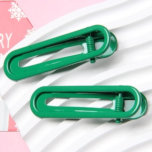 Detail of green glossy metal hair clips in U-shape design on a white textured display