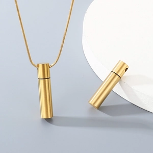 Macro shot of gold cylindrical pendant with snake chain on white display stand