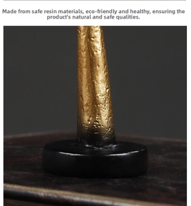 Detailed close-up of textured golden resin ornament with black cylindrical base stand
