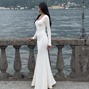 Détail de la robe longue blanche ajustée avec boutons décoratifs et tissu doux et texturé