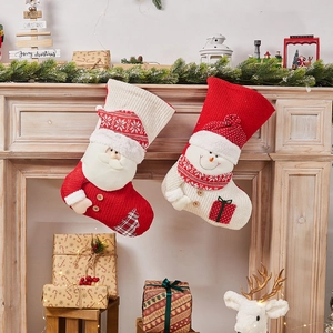Knitted Christmas stockings with Santa and Snowman designs hanging on a festive mantel