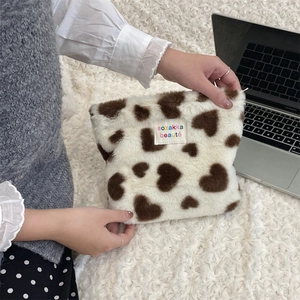 Close-up of plush makeup bag with brown heart leopard pattern held by a person