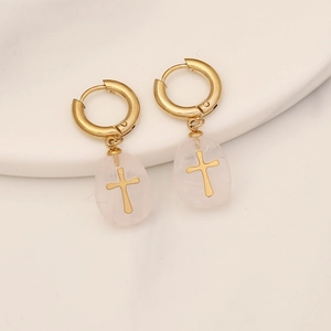 Detailed macro view of gold-plated cross earrings with translucent pink natural stone drops