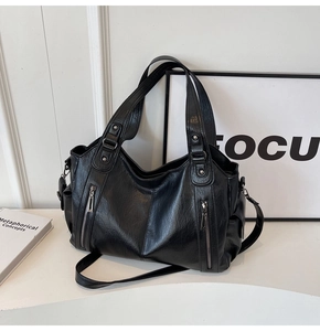 Detailed view of black vintage tote bag with decorative zippers and silver hardware