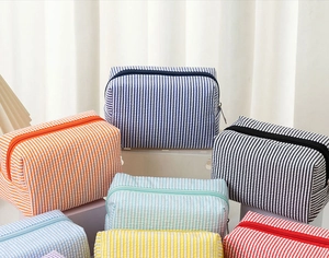 Variety of seersucker makeup bags with vertical stripes arranged on geometric stands