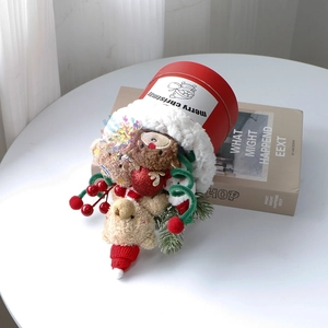 Close-up of a Christmas plush teddy bear and reindeer inside a festive red gift bucket