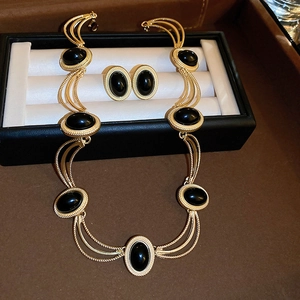 Close-up of vintage gold necklace and oval black gemstone earrings in jewelry box