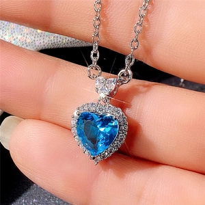 Close-up of heart-shaped blue topaz necklace with silver chain and diamond halo setting