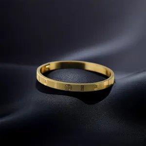 Macro detail of gold stainless steel bangle with engraved coins and grid motifs