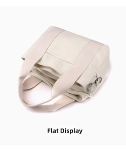 Flat lay of cream canvas tote bag showing top zipper and metal hardware details
