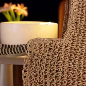 Detailed close-up of woven straw texture and durable handle junction on a beach tote bag