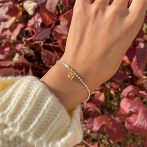Detailed shot of an S925 sterling silver heart charm bracelet on a model's wrist
