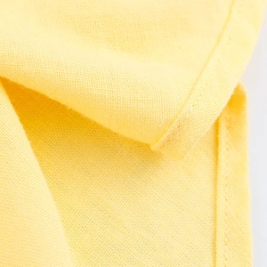 Gros plan sur la texture du tissu en lin jaune vif avec coutures pour chemise d'été