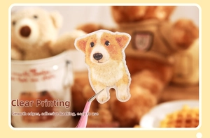 Détail d'un autocollant Corgi appliqué avec une pince sur un fond de papeterie