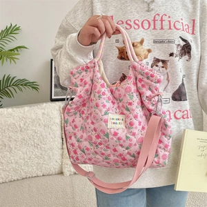 Détail du sac à main matelassé à fleurs roses avec bandoulière et étiquette de marque