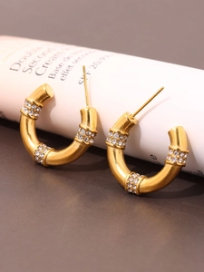 Close-up of C-shaped 18K gold plated earrings featuring four rows of pave set crystals