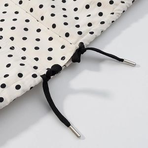 Detail von Polka-Dot-Stoff mit schwarzem Kordelzug und silbernen Metallkordelenden
