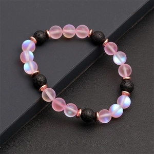 Dettaglio macro di perline rosa occhio di gatto e bracciale in pietra lavica nera e metallo