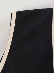 Détail du tissu noir avec bordure tissée crème et finitions de couture précises