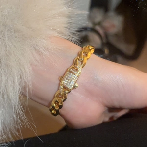 Close-up of a gold Cuban link bracelet with a sparkling crystal-encrusted lock clasp