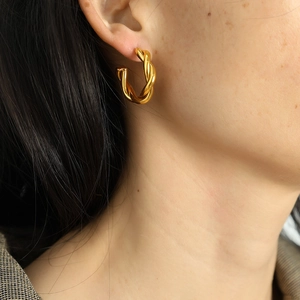 Minimalist twisted gold hoop earrings in a woven double-strand design worn by a female model