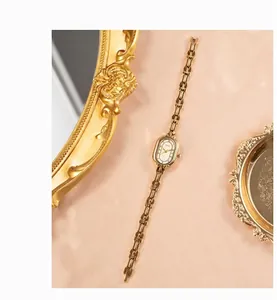 Detail of vintage gold oval quartz watch on pink satin with elegant retro mirror decor