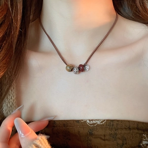 Macro detail of retro stone and wood bead pendant on a leather cord necklace