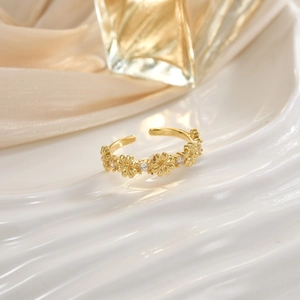 Elegant gold open ring with micro-set zircon floral patterns on polished marble background
