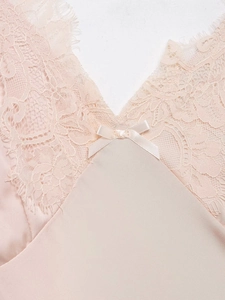 Détail du satin rose avec dentelle délicate et petit nœud ruban sur l'encolure en V