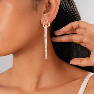 Close-up of golden tassel earrings with rectangular cubic zirconia on model