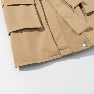 Detail of khaki trench coat featuring flap pockets, metal buttons and premium cotton texture