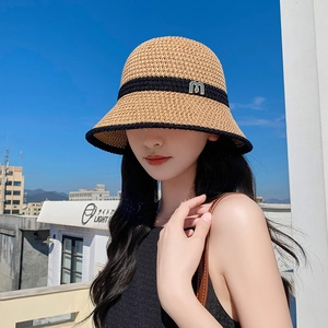 Women's straw bucket hat with black contrast trim and M metal accent in natural light