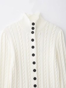 Close-up of white cable knit cardigan featuring black contrast buttons and soft texture