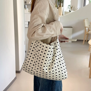 Close-up of a large canvas tote bag with black bow print worn over the shoulder