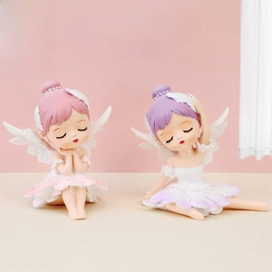 Detail of two ballet girl figurines with fairy wings and floral skirts on a desk