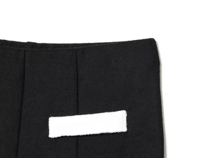 Gros plan sur la texture tricotée gaufrée noire et l'étiquette blanche à la taille