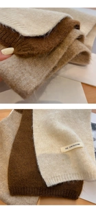 Detail of soft knitted scarves in beige and brown with woven brand label texture