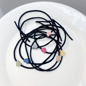 Morandi-colored elastic hair ties with heart charms in a white ceramic dish