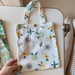 Detailed close-up of a floral cotton handbag featuring a metal button closure and soft patterns