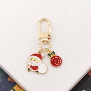 Golden Christmas keychain with enamel Santa Claus and red gift ball charms on white surface