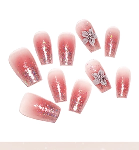Nahaufnahme von rosa Verlaufsnägeln mit feinem Glitzer und 3D-Blumendetails