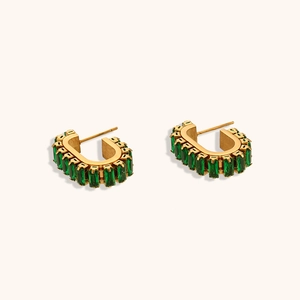 Détail macro de boucles d'oreilles en U dorées avec incrustation de zircon vert rectangle