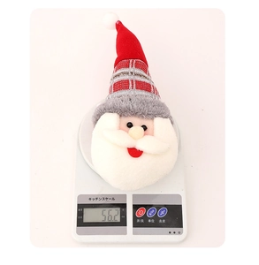 Détail d'embrasse de rideau Père Noël en peluche sur balance affichant 56,2g