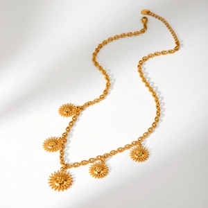 Detail of gold sun face pendants on a stainless steel link chain with shadow accents