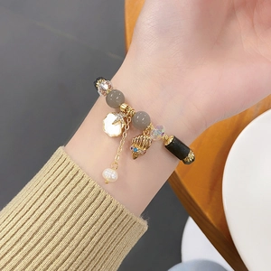 Detail of beaded bracelet with golden star, seashell and bird charms on female wrist