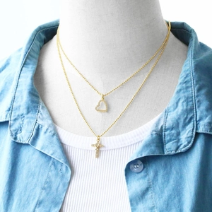 Close-up of double-layer gold heart and cross pendant necklace with sparkling zircons
