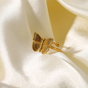Gros plan d'une bague papillon plaquée or 18 carats sur un tissu en soie blanche