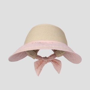 Detailed view of beige straw sun hat with large pink bow and breathable woven texture