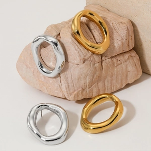 Minimalist irregular oval earrings in gold and silver finish on natural stone background